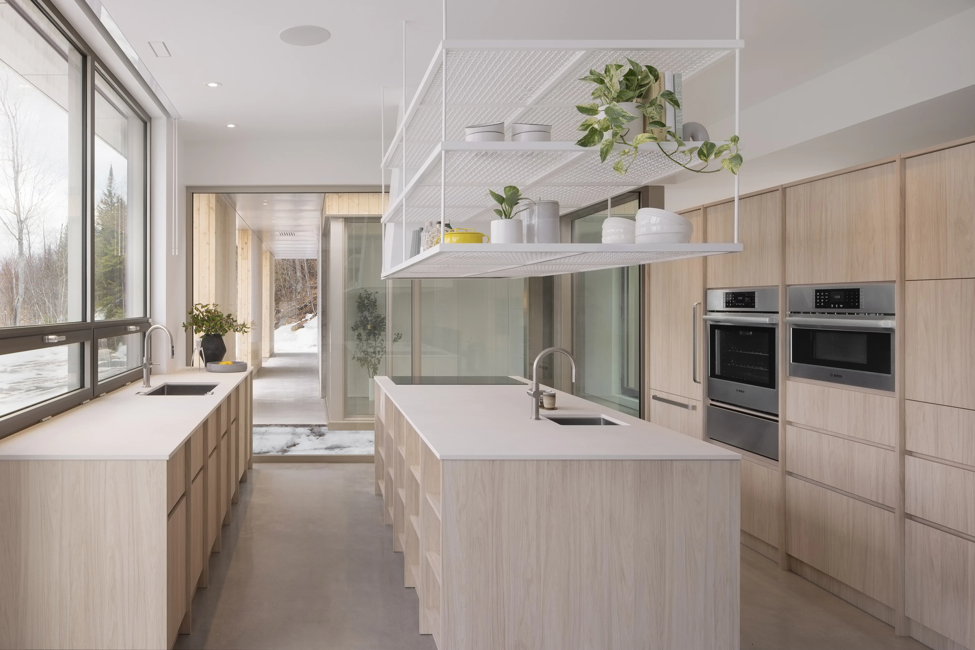 Modern kitchen with light wood cabinets, sleek appliances, and large windows letting in natural light.