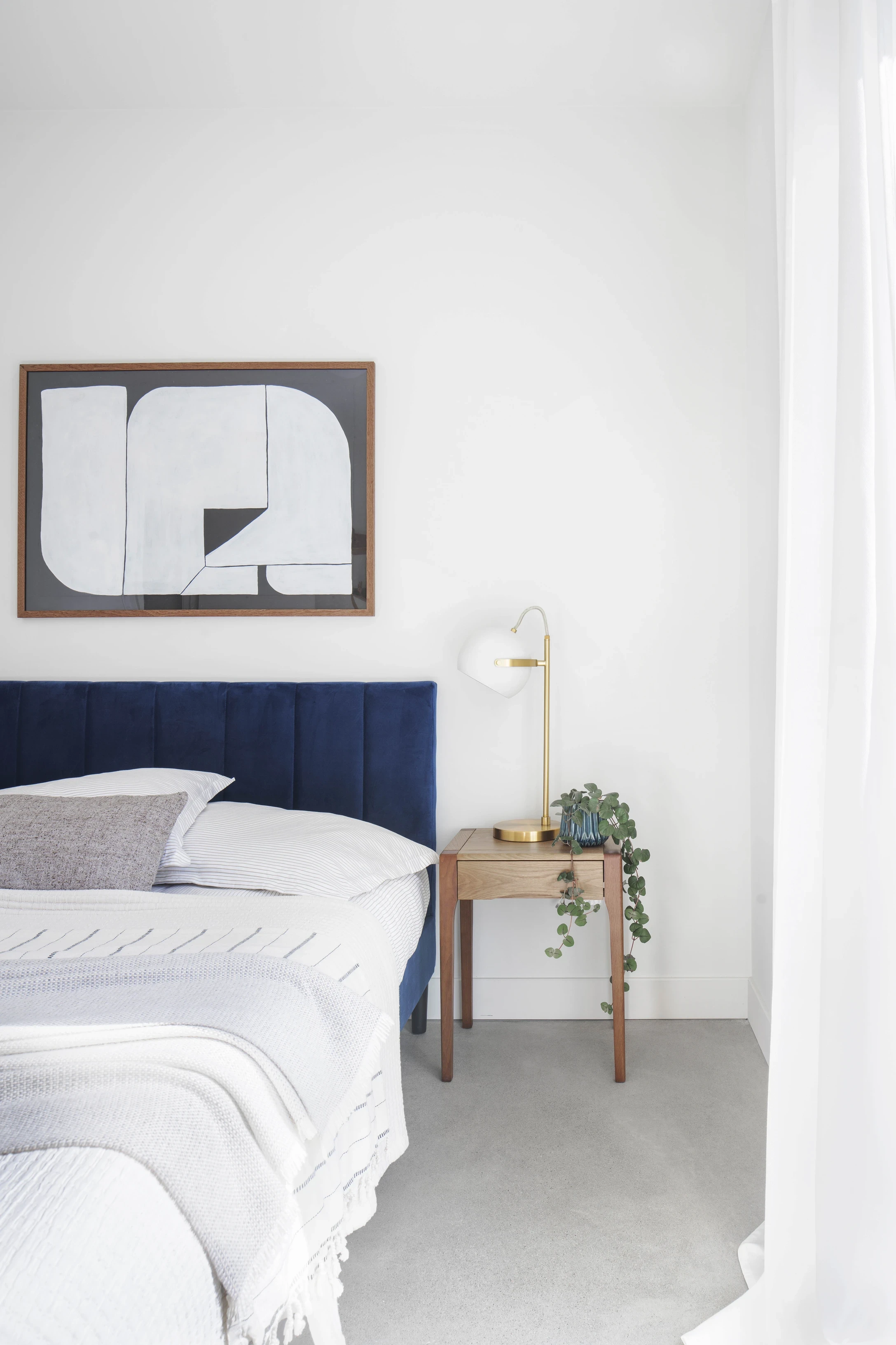 Chambre lumineuse au design minimaliste, lit rembourré et mobilier en bois clair, photographie architecturale résidentielle.