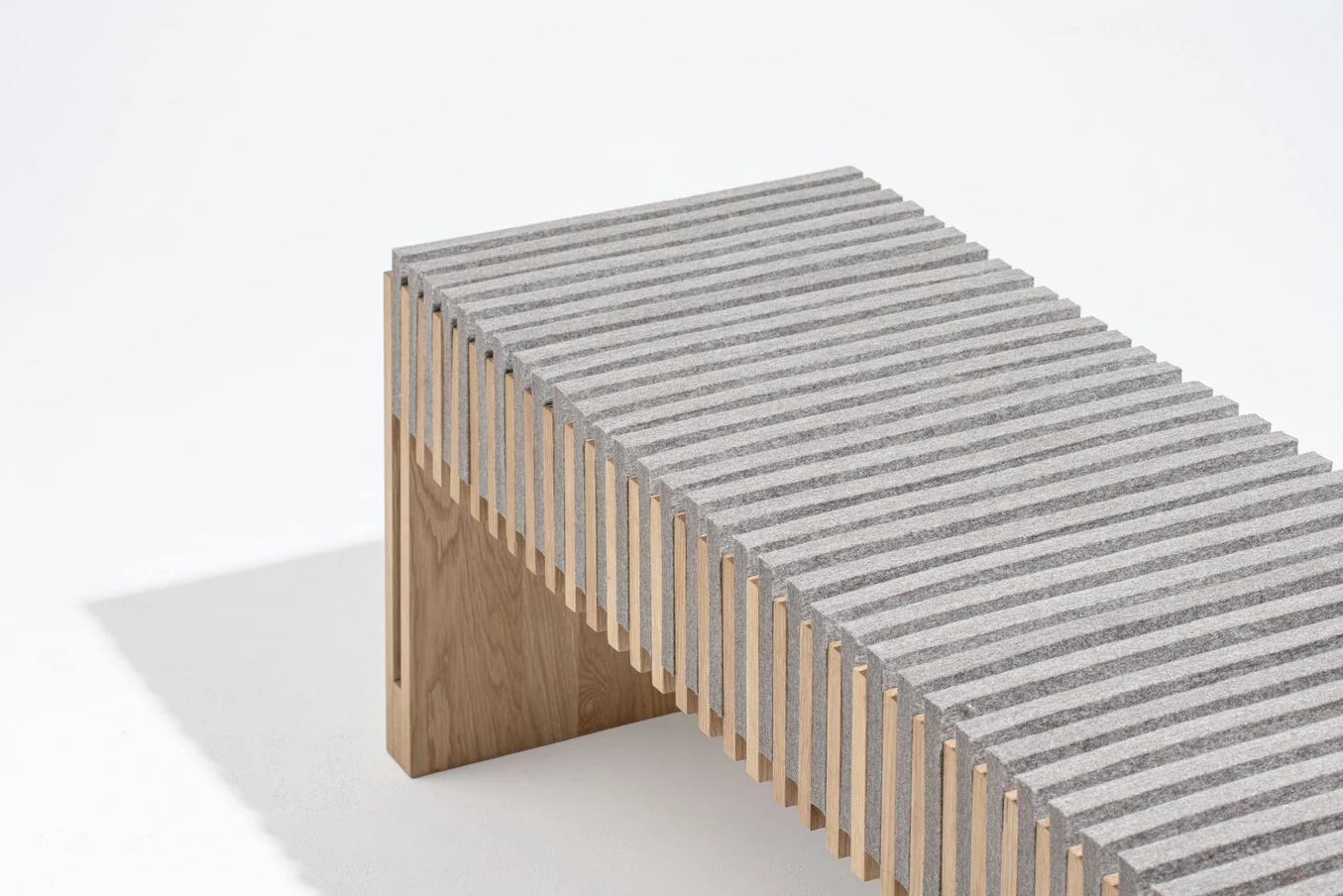 Détail de l’assise nervurée en bois et matériau minéral, composition linéaire.